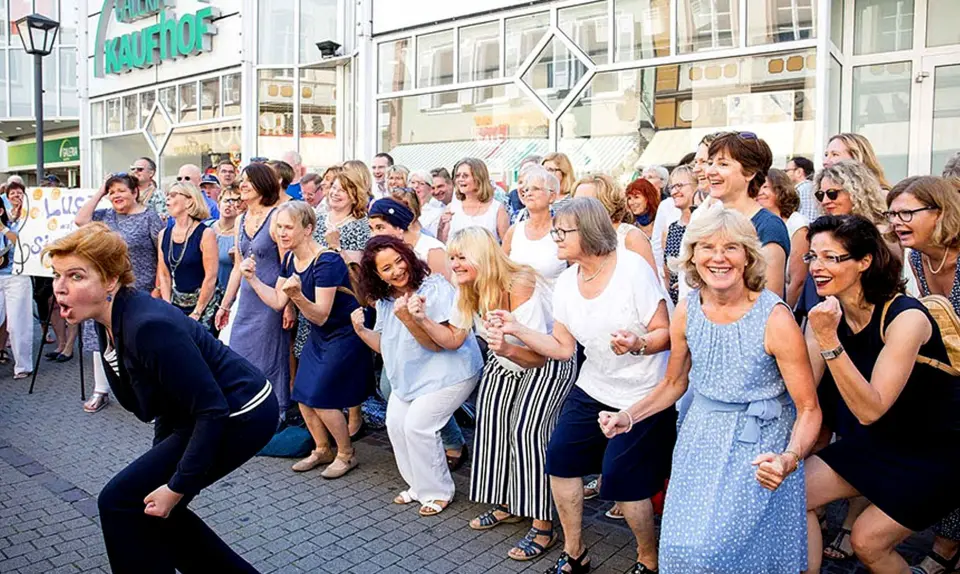 Singende Gruppe in der Fußgängerzone, eine Frau gestikuliert